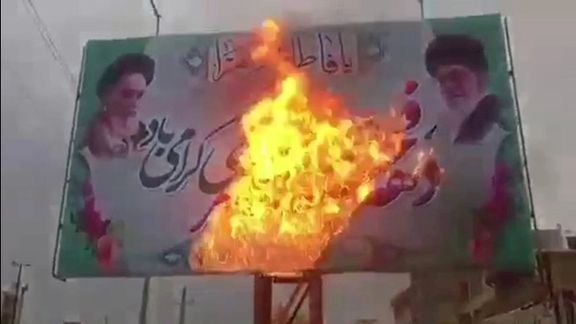 A banner of Iran’s Supreme Leader Ali Khamenei and Islamic Republic’s founder Ruhollah Khomeini being burnt