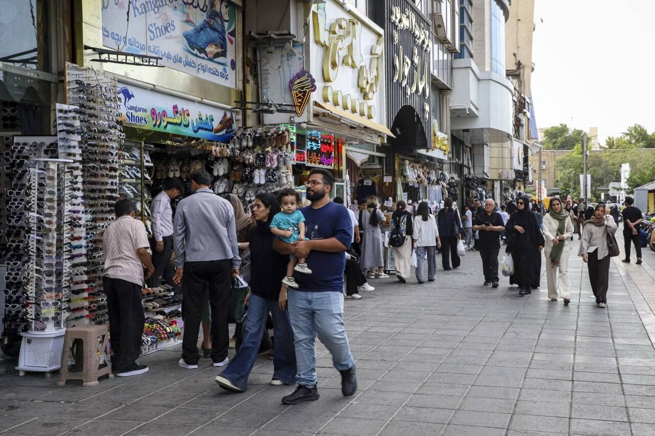 Shoppers walk past stores in Iran's northeasternt city of Mashhad.