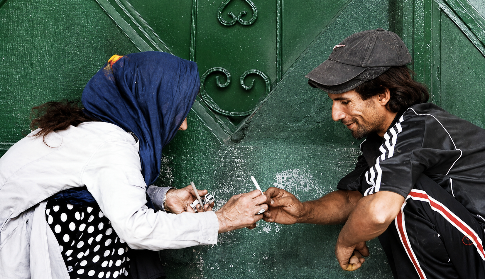 File photo shows two people with substance use disorders preparing drugs together in an outdoor area in Iran.