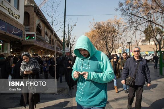 People looking at their cellphones on a street near Tehran's bazaar