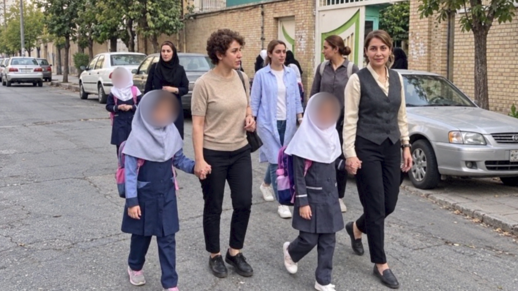 Iranian mothers accompany their daughters on the first day of school in Tehran in September. The image was reframed using AI to extend the background horizontally. 