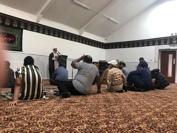 A cleric speaks to mosque goers in the Islamic Centre in Scotland.