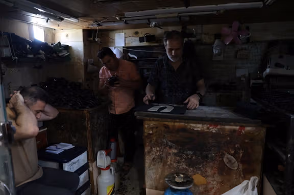 Shoemakers work following a power outage at a shoe workshop in Tehran, Iran, June 3, 2025.