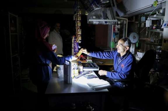 People shop in a grocery store under a portable electric light during a power cut near Bhamdoun, Lebanon, October 9, 2021.