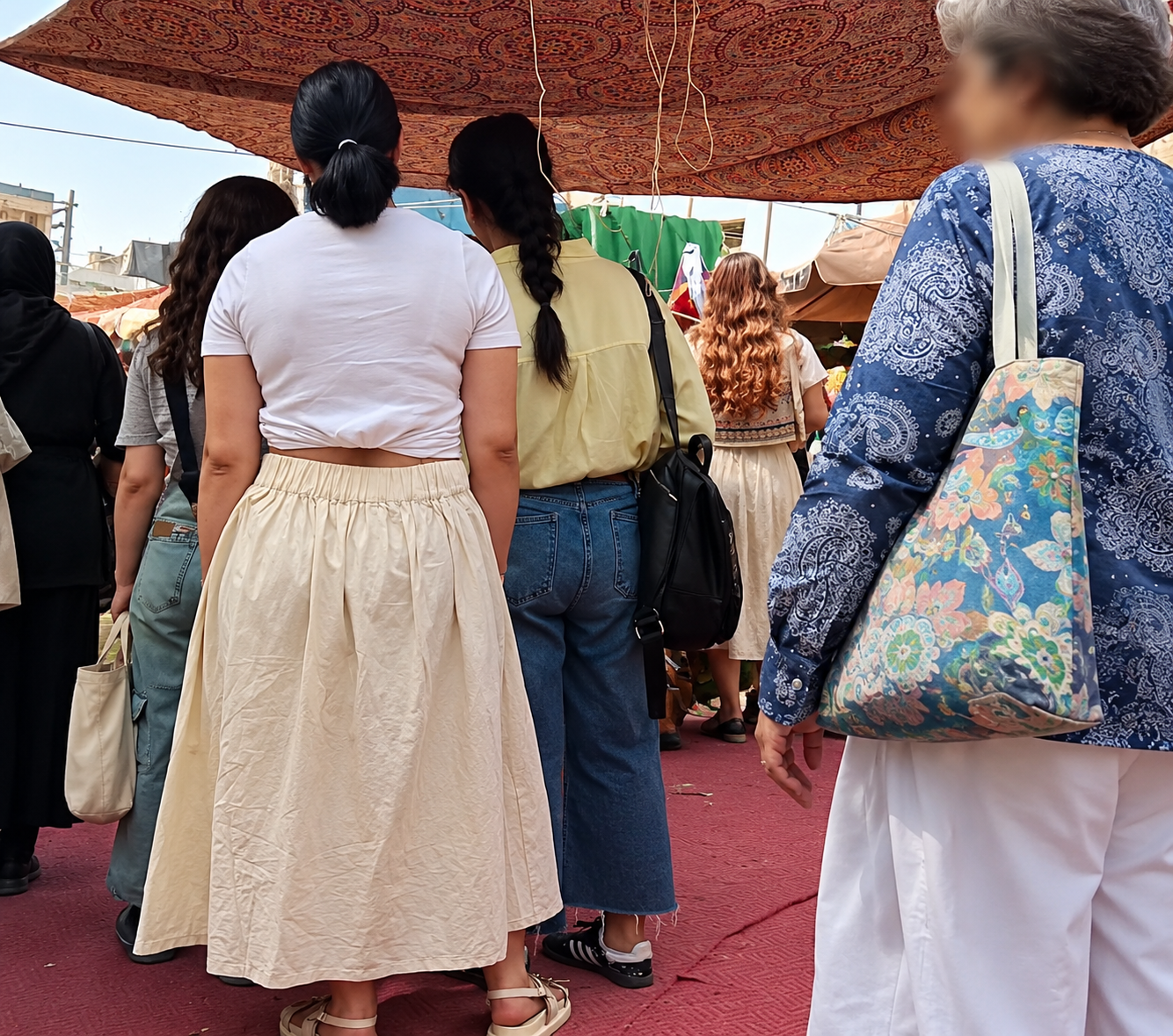 Women are seen at an outdoor market in Iran without the mandatory hijab in September 2026.