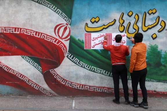 Iranian men put campaign posters on a wall during the last day of election campaigning in Tehran, Iran, February 28, 2024.