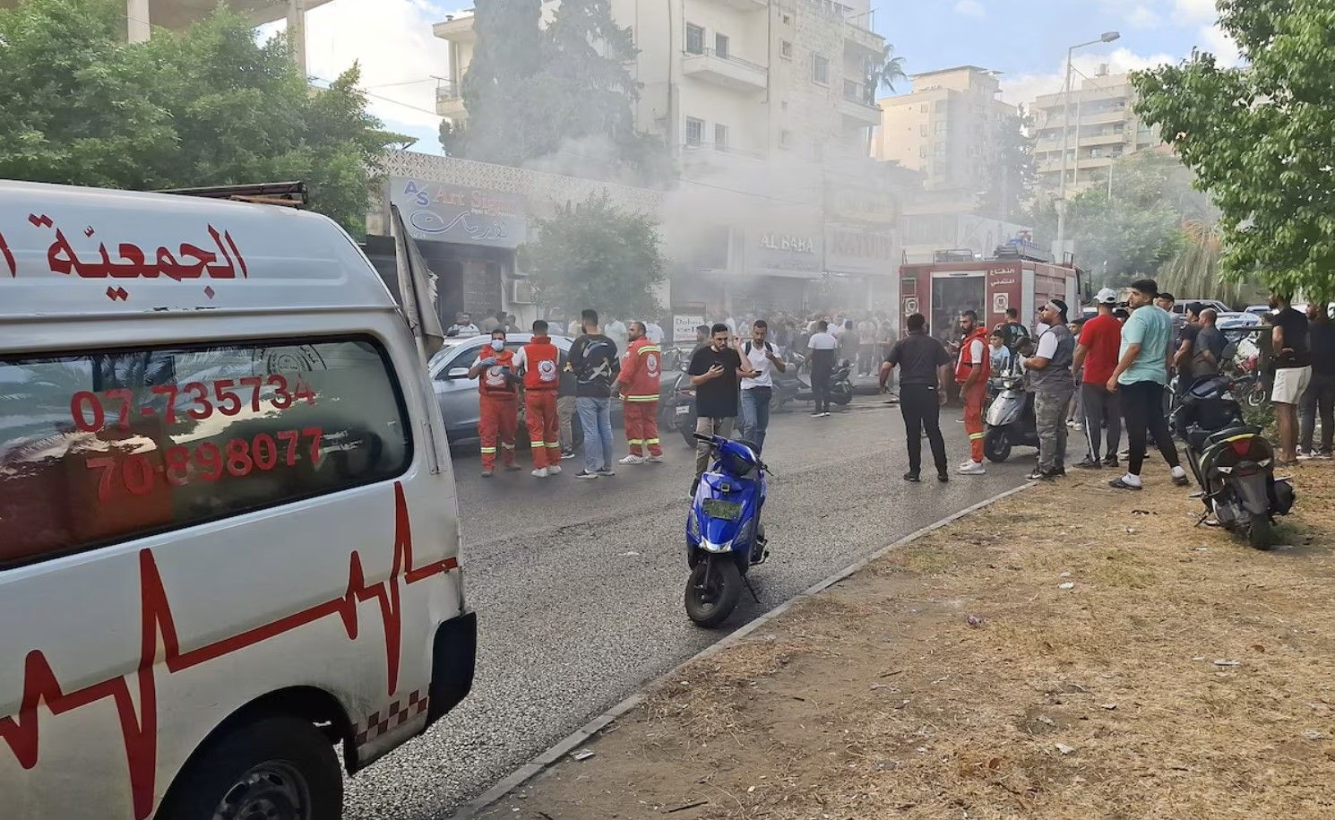 Smoke rises from a mobile shop as civil defence members gather in Sidon, Lebanon September 18, 202