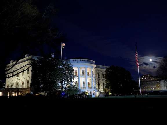 The moon rises next to the White House in Washington, D.C., U.S., December 4, 2025.
