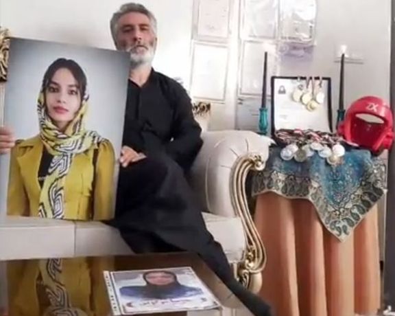 Mahsa Moguei's father holding a photo of her daughter