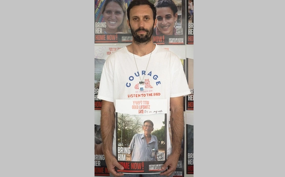 Daniel Lifshitz holding a photo of his grandfather Oded Lifshitz, still a hostage in Gaza.