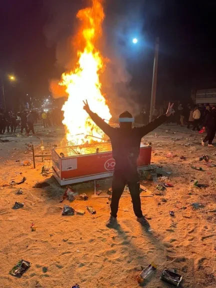 A protester in Ilam province flashes a victory sign after people stormed an allegedly state-linked chain supermarket, tearing open rice bags and spilling their contents onto the ground.