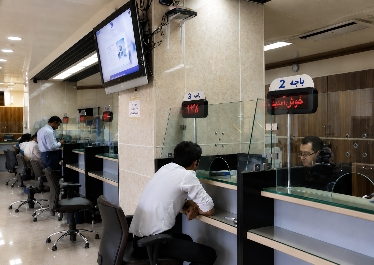 A customer speaks with a bank teller at a branch in Iran.