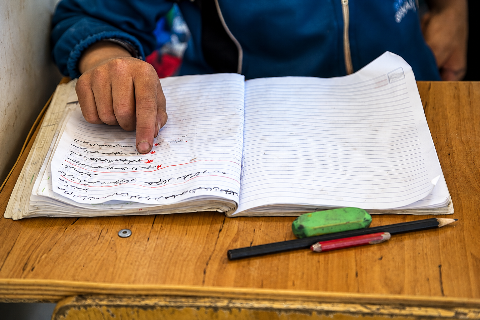A student points to writing in a notebook at a school in Iran.