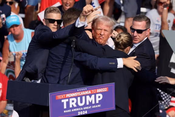 Republican presidential candidate and former US President Donald Trump gestures with a bloodied face while he is assisted by US Secret Service personnel after he was shot in the right ear during a campaign rally at the Butler Farm Show in Butler, Pennsylvania, US, July 13, 2024.