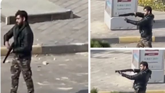 A security agent firing a shotgun at protesters in Esfahan on November 26, 2021