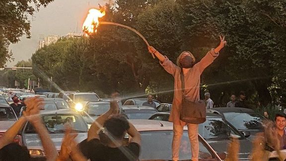 A young woman is burning her headscarf in defiance in Tehran on September 19, 2022