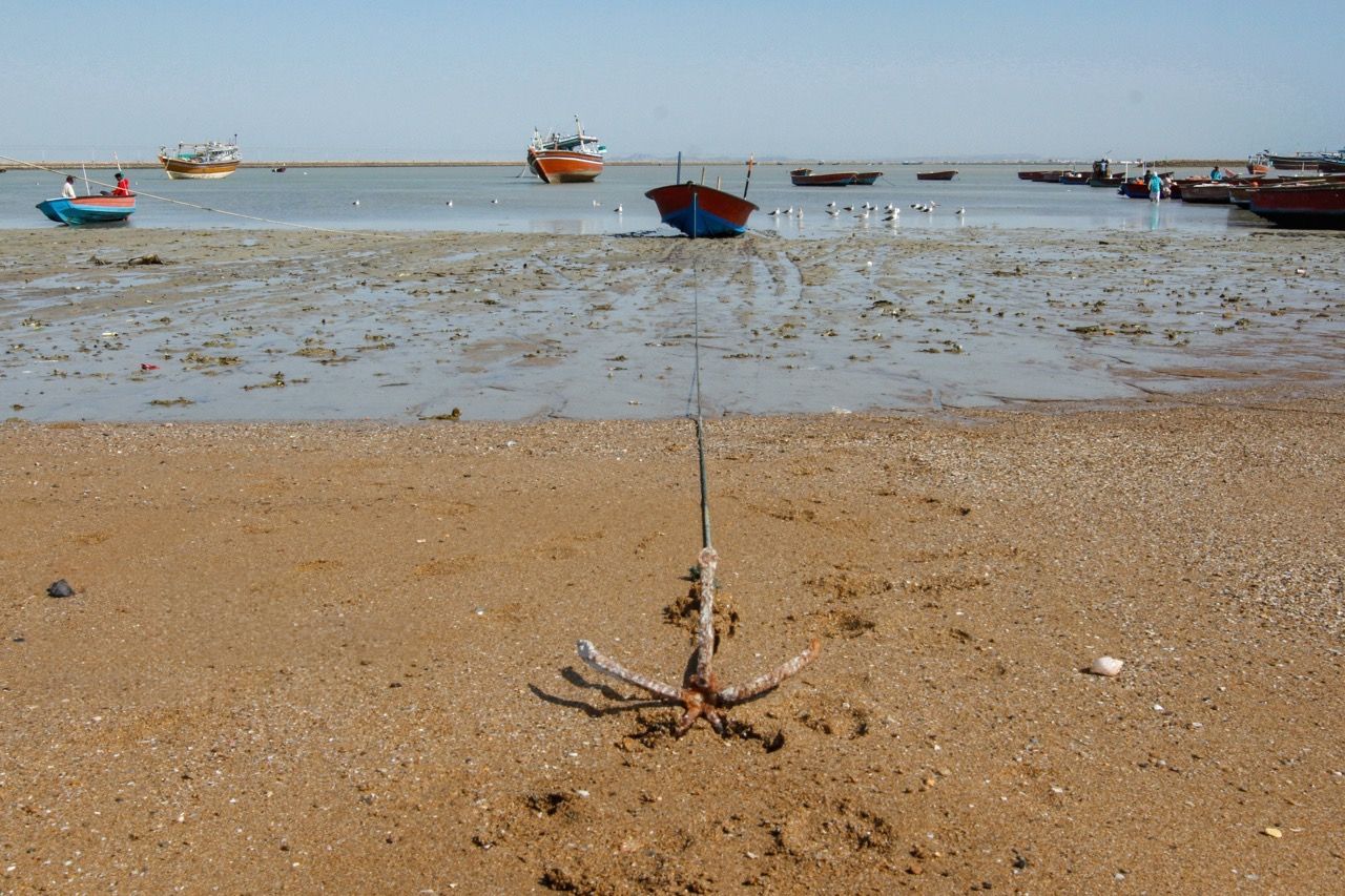 Fishing boats sit grounded at low tide along the coast in the southeastern Iranian port of Konarak, July 20, 2026