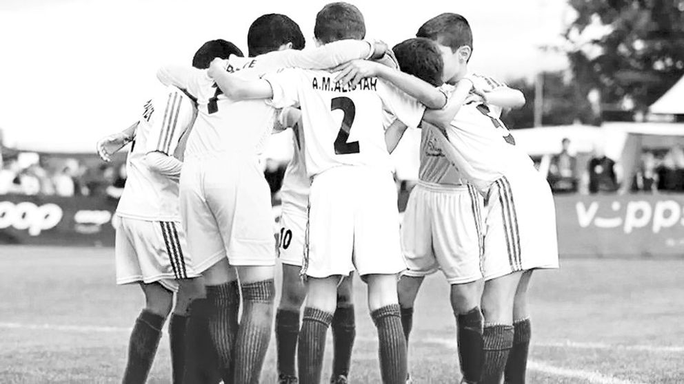 A number of teenage football players huddling before a match  