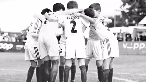 A number of teenage football players huddling before a match