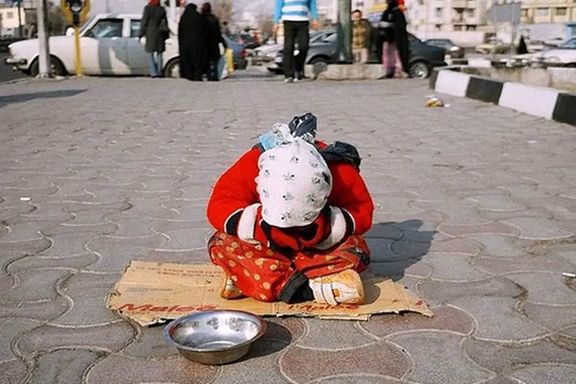 A little girl sitting on the sidewalk asking for change, Iran