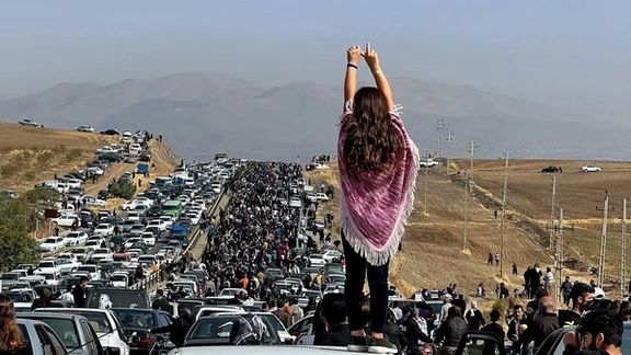 A woman standing on top of a vehicle as thousands make their way towards the cemetery in Saqqez, Mahsa Amini’s hometown in the western Iranian province of Kordestan, to mark the 40th day since her death