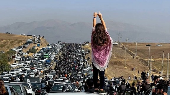 A woman standing on top of a vehicle as thousands make their way towards the cemetery in Saqqez, Mahsa Amini’s hometown in the western Iranian province of Kordestan, to mark the 40th day since her death