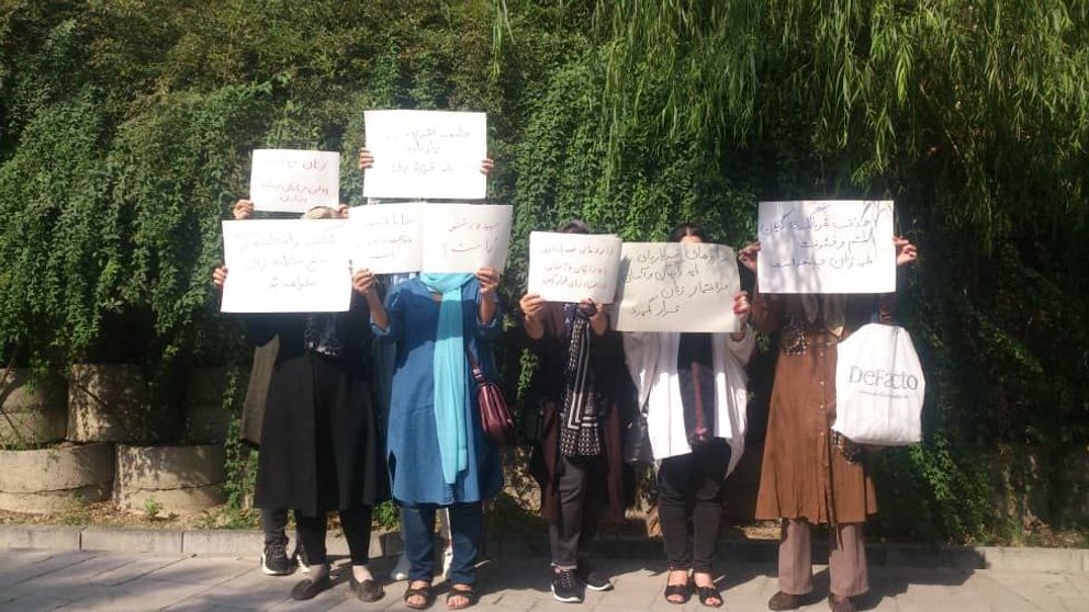 Woemn in Tehran street holding placards in protest, August 15, 2022