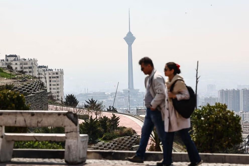 A couple walk in a park overlooking Tehran, with the iconic Milad Tower seen in the background, April 1, 2026.