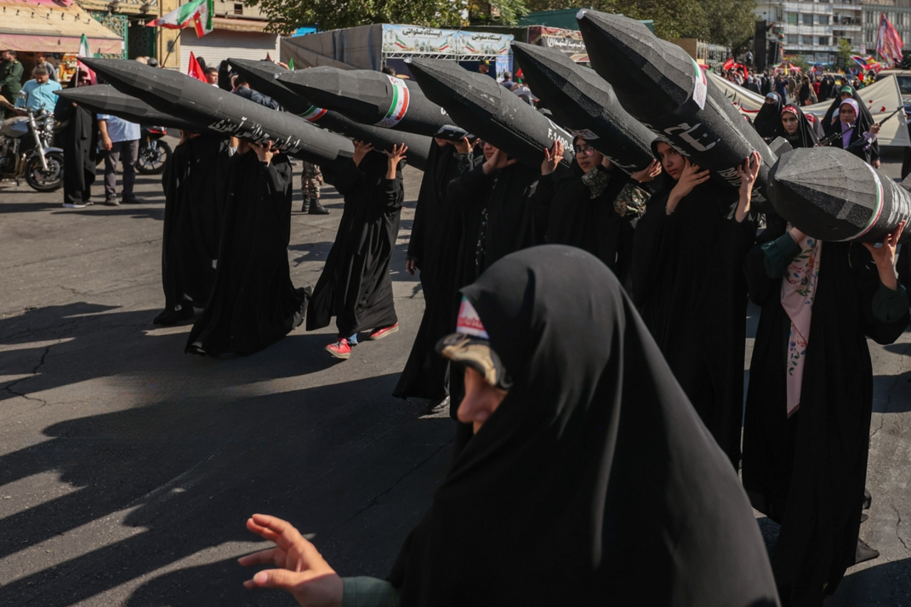 Women carry models of Iranian missiles during the state-organized Janfadayan-e Iran parade in Tehran on September 18, 2026.