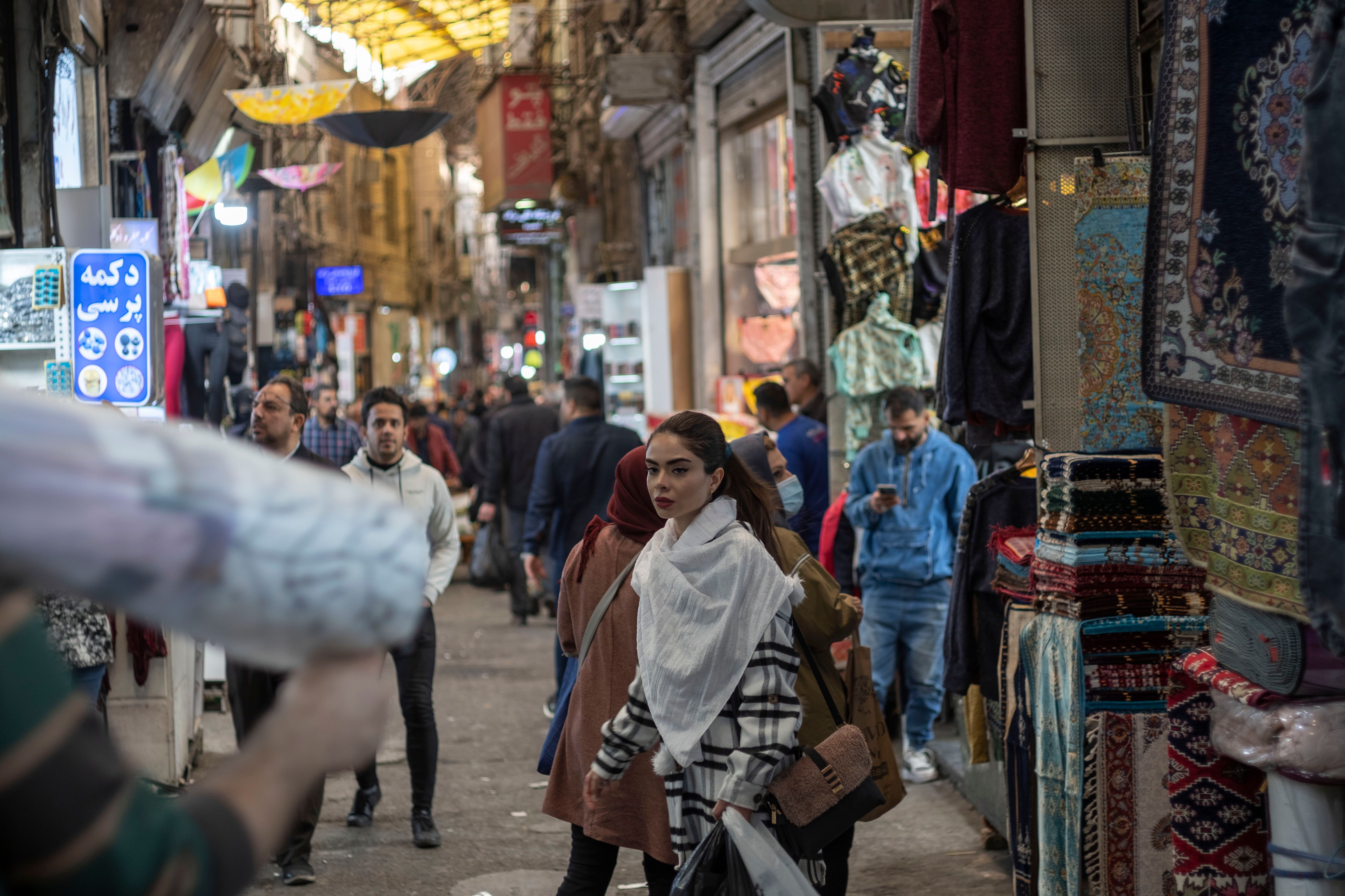 An Iranian young woman looks on as she and her mother walk along an area in Tehran Grand Bazaar (Market), December 3, 2022. (