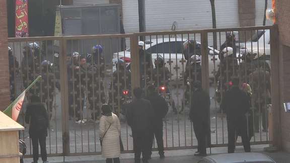 Security forces stand behind a gate outside Sina Hospital in Tehran, where witnesses said some protesters had sought refuge during clashes, January 6, 2026