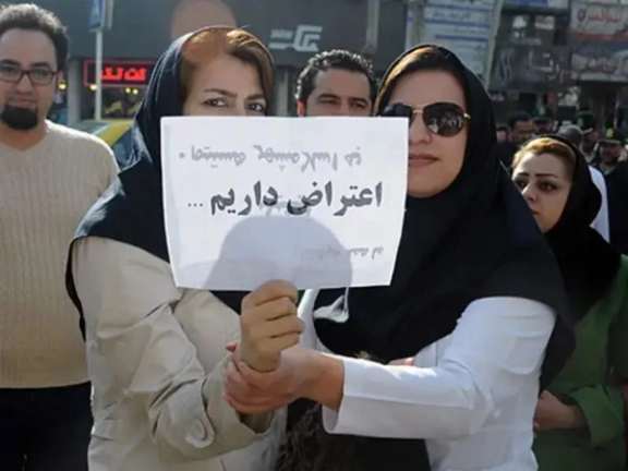 Two nurses holding a placard that reads 'we have objections'