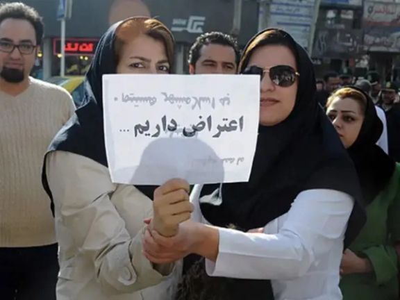 Two nurses holding a placard that reads 'we have objections'