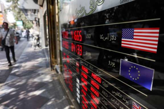 People walk past a sign at a currency exchange as the value of the Iranian Rial drops, in Tehran, Iran, October 5, 2025.