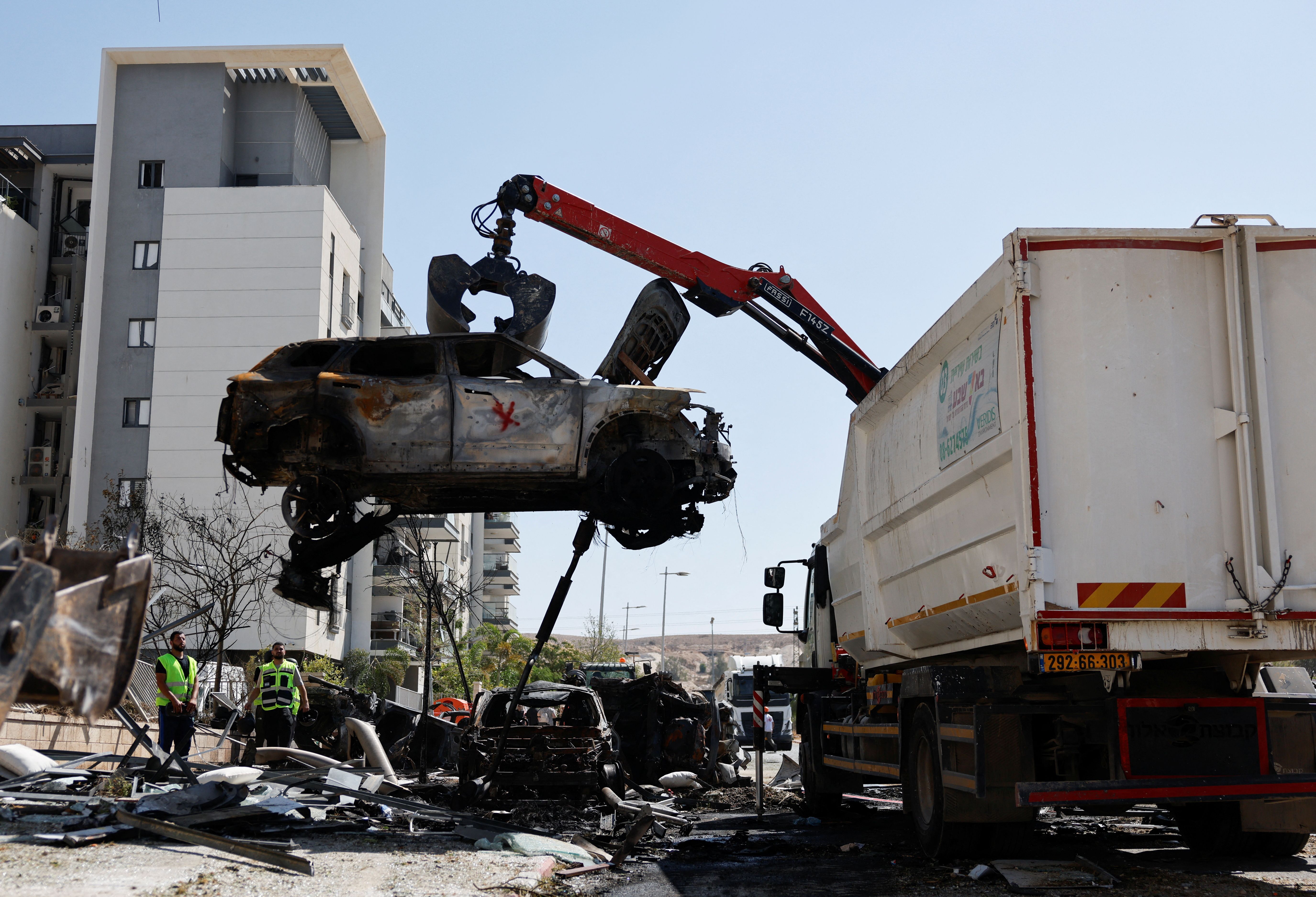 A crane lifts a destroyed car at an impact site following Iran's missile strike on Israel, in Be'er Sheva, Israel, June 20, 2025. 