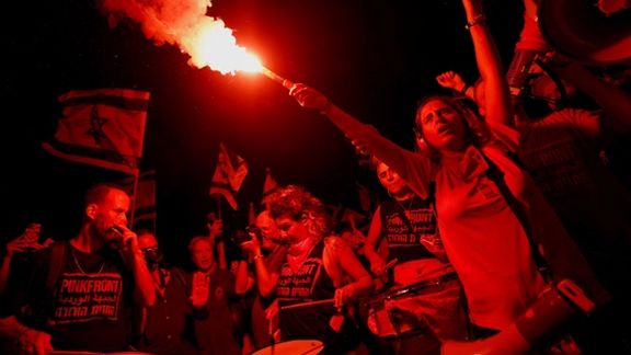 A protester holds a flare during a demonstration against Israeli Prime Minister Benjamin Netanyahu and his nationalist coalition government's judicial overhaul, days after a parliament vote on a contested bill that limits the Supreme Court's powers to void some government decisions, in Tel Aviv, Israel July 27, 2023.