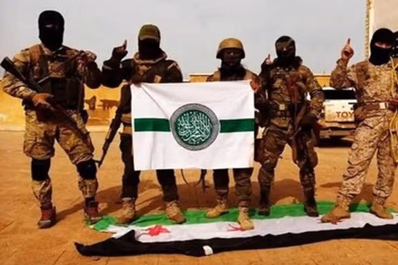 اعضا حرکت مجاهدین اهل سنت ایران که پرچم خود را دست گرفته و پرچم استقلال سوریه را زیر پا گذاشتهاند