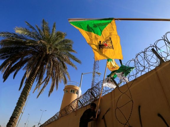 A member of Hashd al-Shaabi (paramilitary forces) holds a flag of Kataib Hezbollah militia group during a protest to condemn air strikes on their bases, outside the main gate of the US Embassy in Baghdad, Iraq December 31, 2019.