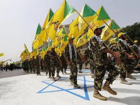 Iranian-backed militia Kataib Hezbollah hold the party's flags as they walk along a street painted in the colours of the Israeli flag during a parade marking the annual Quds Day, or Jerusalem Day, on the last Friday of the Muslim holy month of Ramadan, in Baghdad in July 25, 2014.