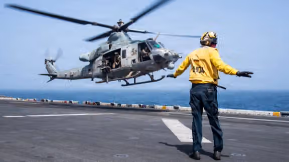 A US sailor directs a UH-1Y Venom helicopter from the USS Boxer in the Arabian Sea during enforcement of the US blockade against Iran. (CENTCOM/X)