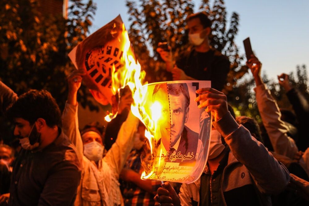 Demonstrators gather outside the French Embassy in Tehran in October 2020, protesting the publication of caricatures of the Prophet Muhammad. Protesters hold placards depicting French President Emmanuel Macron, burn his image, and call for a boycott of French goods.