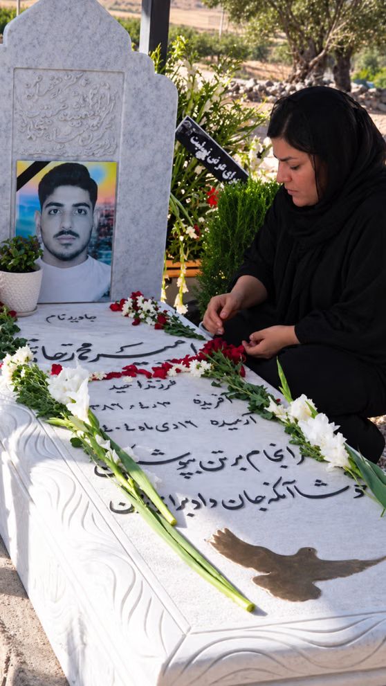 A woman places flowers on the grave of Amirmohammad Hatami, an 18-year-old mechanic from Shahin Shahr who was killed after being wounded and detained on January 9, 2026.