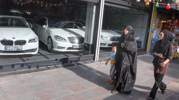 People passing by a shop for luxury cars in Tehran