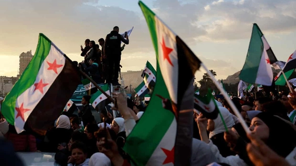 People gather for a celebration called by Hayat Tahrir al-Sham in Damascus on Friday.