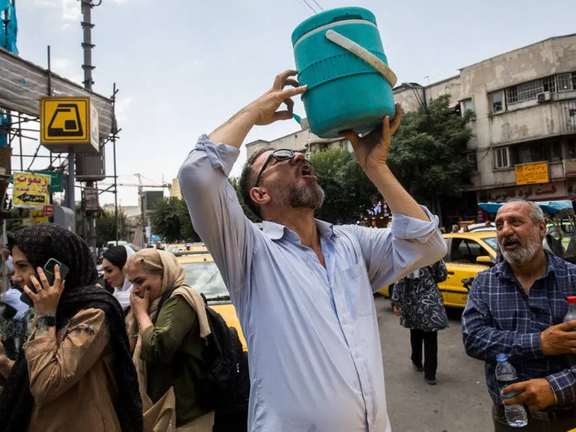 A taxi driver drinks water from a cool box in a hot summer day, Tehran, Iran, July 2025