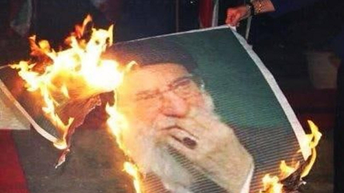 A burning banner of Iran’s ruler Ali Khamenei