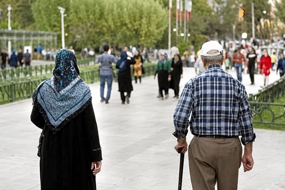 An elderly couple walks through a public park in Iran.