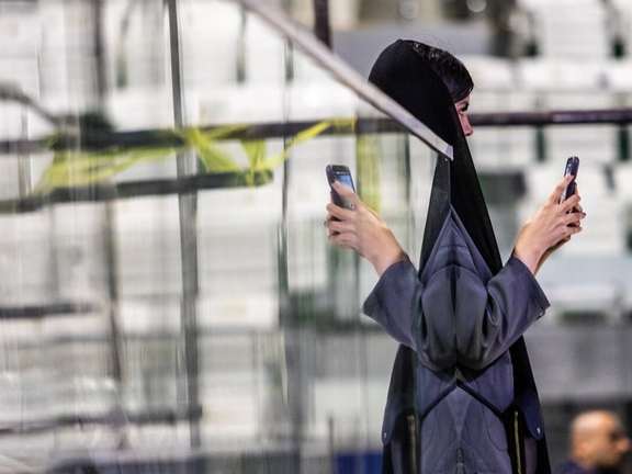 A young woman takes a picture with her mobile phone on the sidelines of a short film festival in Tehran, Iran, November 2025