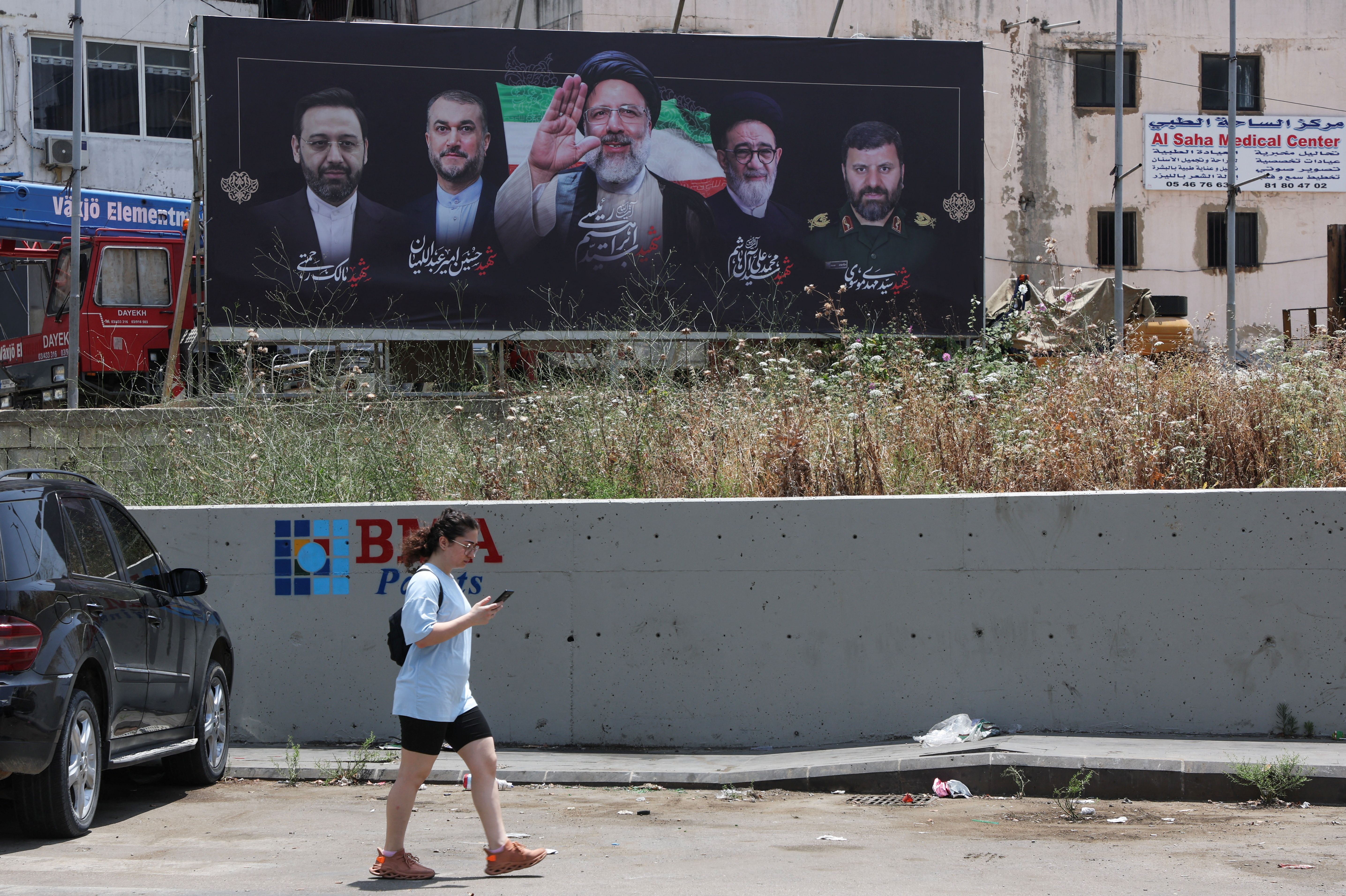 A woman walks past a poster depicting late Iranian President Ebrahim Raisi and Foreign Minister Hossein Amirabdollahian who were killed along with other officials in a helicopter crash, in Beirut suburbs, Lebanon May 22, 2024.