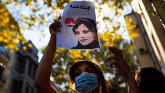 Protestor in Tehran holding up a photo of Mahsa Amini, killed by hijab police in September 2022